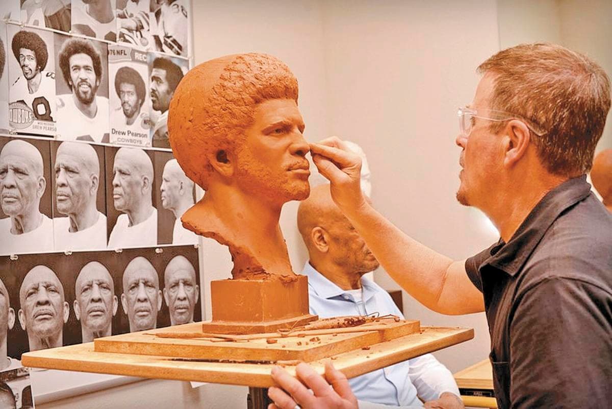 Scott Myers sculpting Drew Pearson's portrait bust in the studio