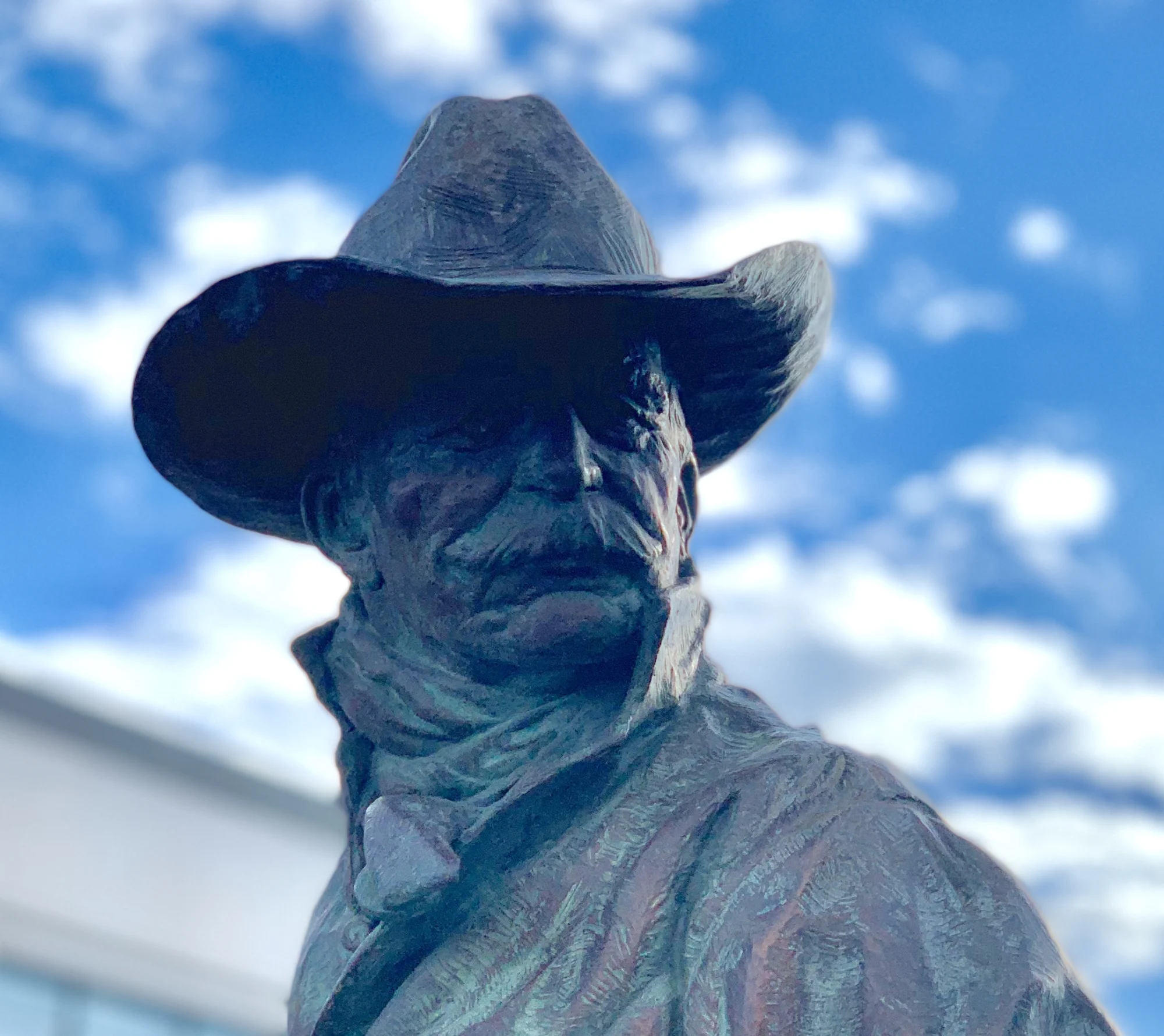 Bronze Western figure sculpture by Scott Myers against a blue sky