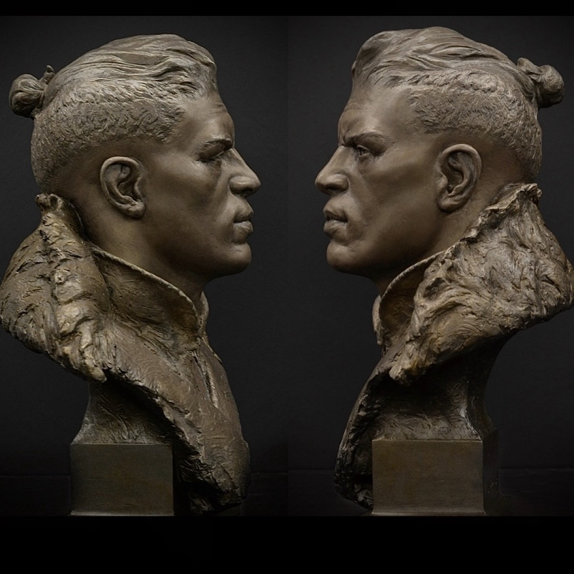 Two bronze profile views of the Resilient portrait sculpture facing one another