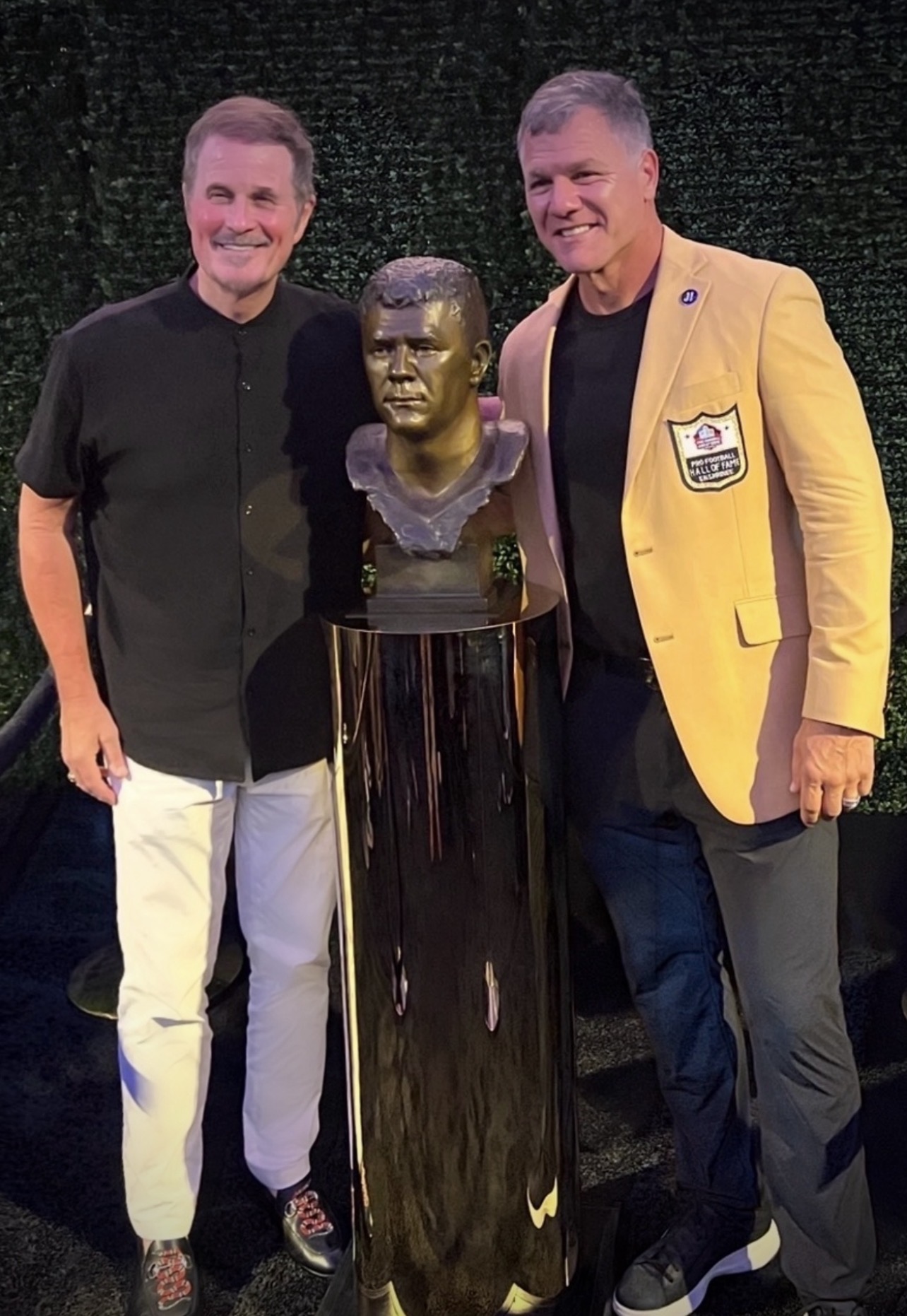 Adam Vinatieri and sculptor Scott Myers standing with Vinatieri’s Pro Football Hall of Fame portrait bust